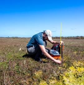 Ecologist setting up a water level logger in a wetland